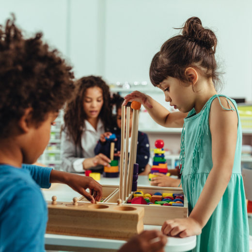A group of children playing with wooden blocks in a classroom.