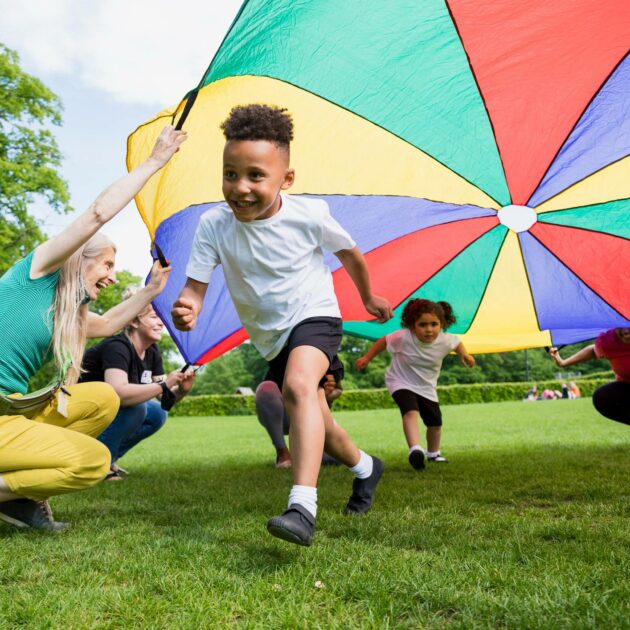 A group of children playing with a colorful parachute in a park.