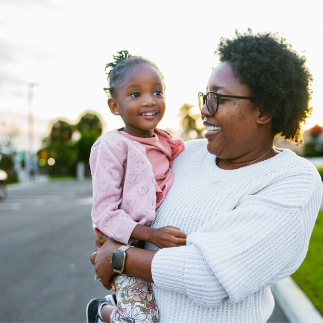 Woman holding child outside.